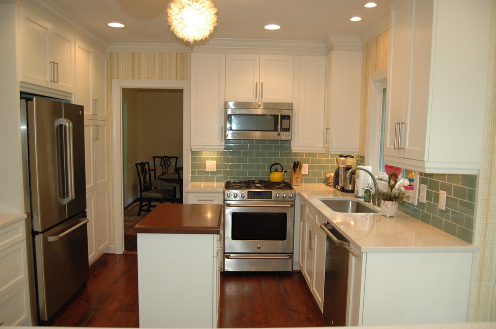 Design ideas for a traditional kitchen in Raleigh with shaker cabinets, white cabinets, engineered stone countertops, white splashback, metro tiled splashback, stainless steel appliances, dark hardwood flooring and an island.