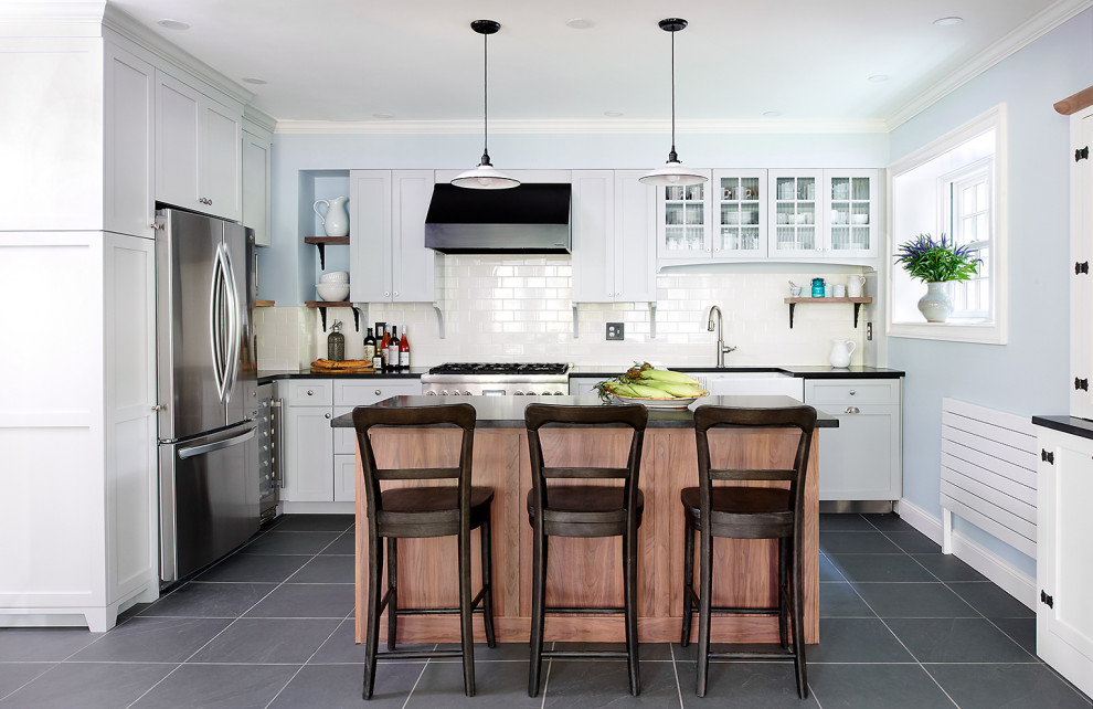 Inspiration for a mid-sized transitional u-shaped slate floor and gray floor eat-in kitchen remodel in Philadelphia with a farmhouse sink, shaker cabinets, granite countertops, white backsplash, ceramic backsplash, stainless steel appliances, an island, black countertops and white cabinets