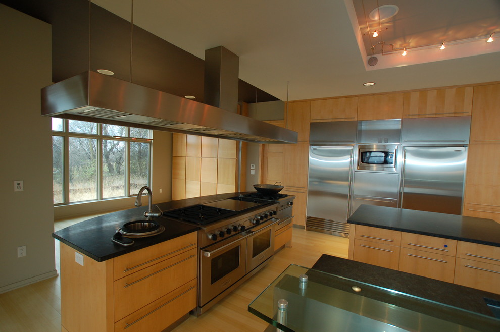 This is an example of an expansive contemporary single-wall kitchen/diner in Other with a submerged sink, flat-panel cabinets, light wood cabinets, granite worktops, stainless steel appliances, bamboo flooring and multiple islands.