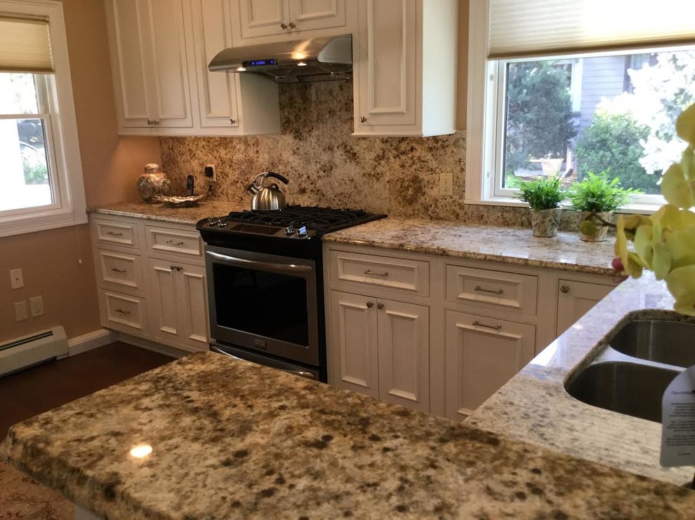 Exempel på ett avskilt, mellanstort klassiskt u-kök, med en dubbel diskho, luckor med profilerade fronter, vita skåp, granitbänkskiva, brunt stänkskydd, stänkskydd i sten, rostfria vitvaror, mörkt trägolv, en halv köksö och brunt golv