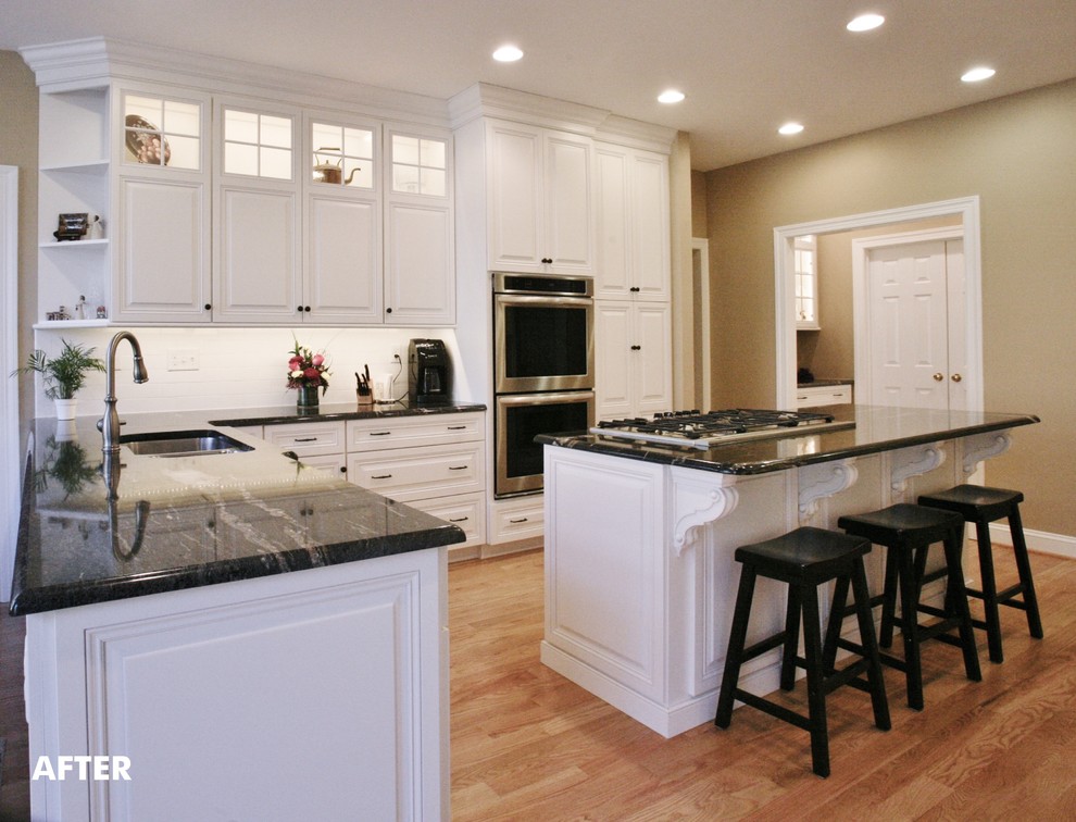 Example of a large classic l-shaped light wood floor eat-in kitchen design in Philadelphia with a double-bowl sink, glass-front cabinets, white cabinets, granite countertops, white backsplash, ceramic backsplash, stainless steel appliances and an island