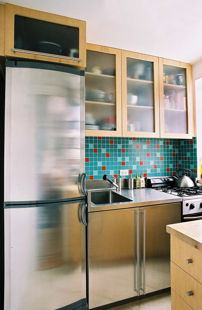 Foto di una piccola cucina parallela moderna chiusa con lavello integrato, ante lisce, ante in legno chiaro, top in acciaio inossidabile, paraspruzzi blu, paraspruzzi con piastrelle di vetro, elettrodomestici in acciaio inossidabile, pavimento con piastrelle in ceramica e nessuna isola