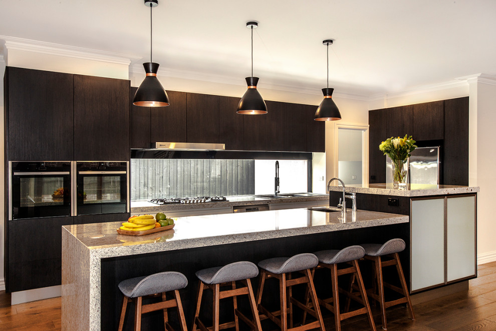 Large contemporary galley open plan kitchen in Melbourne with a double-bowl sink, flat-panel cabinets, dark wood cabinets, granite worktops, window splashback, stainless steel appliances, medium hardwood flooring, an island, brown floors and multicoloured worktops.