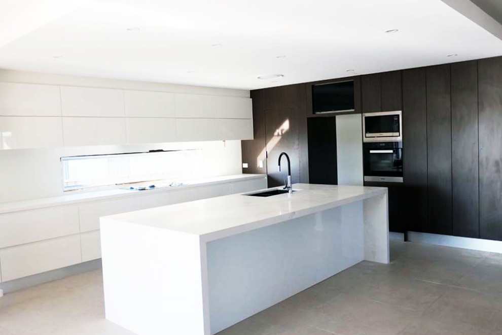 Photo of a medium sized contemporary galley open plan kitchen in Sydney with a single-bowl sink, recessed-panel cabinets, white cabinets, marble worktops, white splashback, metro tiled splashback, white appliances, ceramic flooring, an island and white worktops.