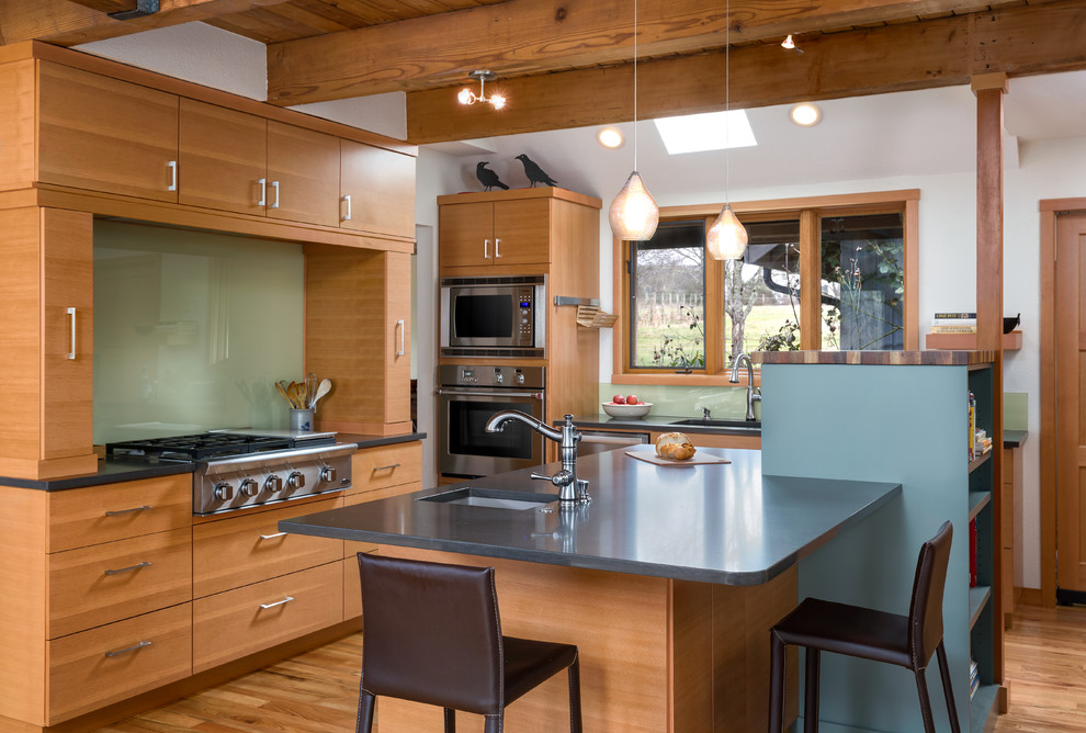 Open concept kitchen - mid-sized contemporary l-shaped light wood floor open concept kitchen idea in Portland with an undermount sink, flat-panel cabinets, light wood cabinets, quartz countertops, green backsplash, glass sheet backsplash, stainless steel appliances and an island