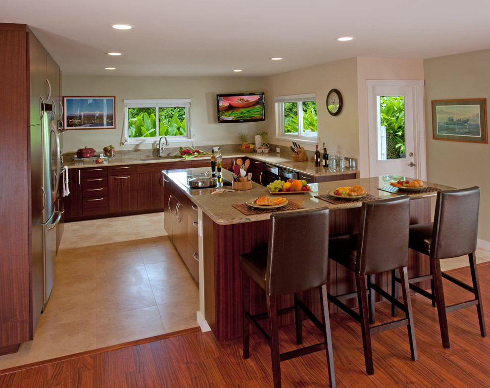 ハワイにある広いトロピカルスタイルのおしゃれなキッチン (アンダーカウンターシンク、フラットパネル扉のキャビネット、中間色木目調キャビネット、御影石カウンター、シルバーの調理設備、セラミックタイルの床、ベージュの床) の写真