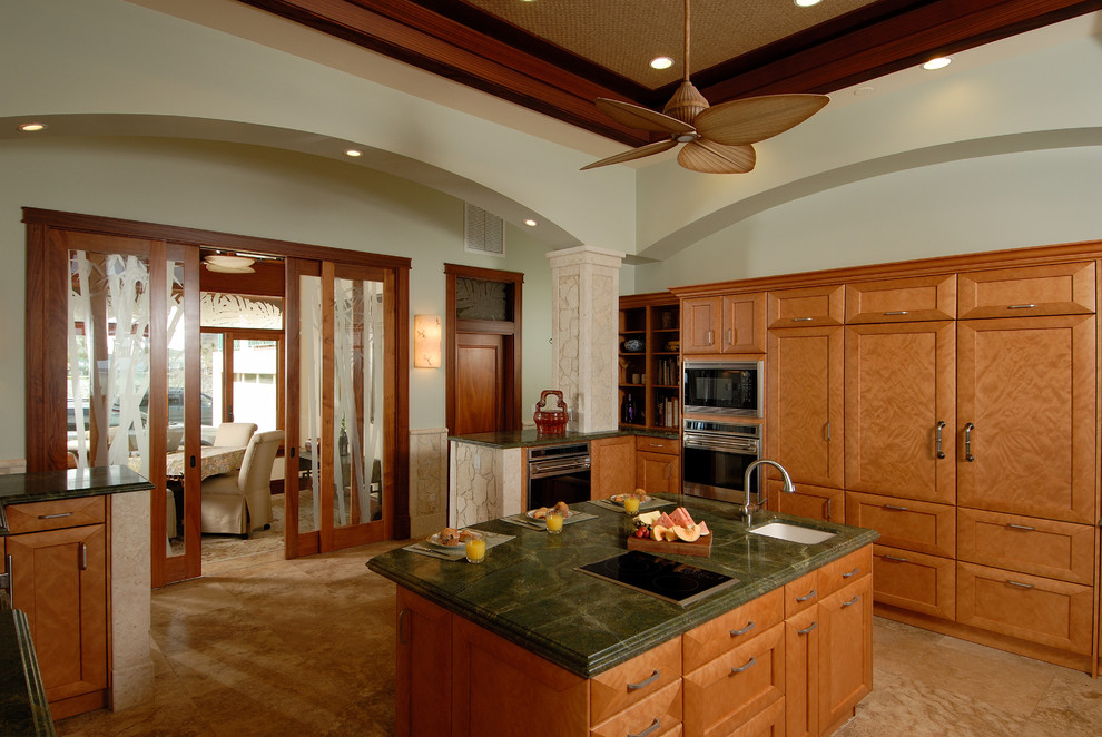 Exempel på ett stort exotiskt u-kök, med skåp i mellenmörkt trä, granitbänkskiva, rostfria vitvaror, en köksö, en undermonterad diskho, skåp i shakerstil, grönt stänkskydd, stänkskydd i sten, travertin golv och beiget golv