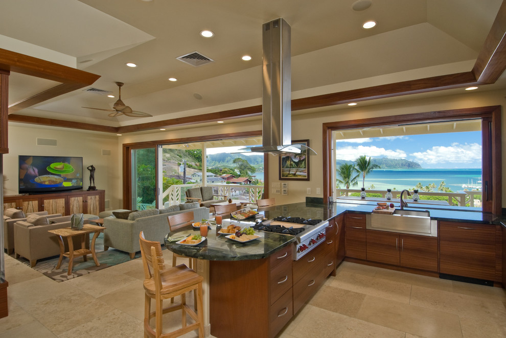 ハワイにある広いトロピカルスタイルのおしゃれなキッチン (エプロンフロントシンク、セラミックタイルの床、ベージュの床、フラットパネル扉のキャビネット、中間色木目調キャビネット、御影石カウンター、シルバーの調理設備) の写真