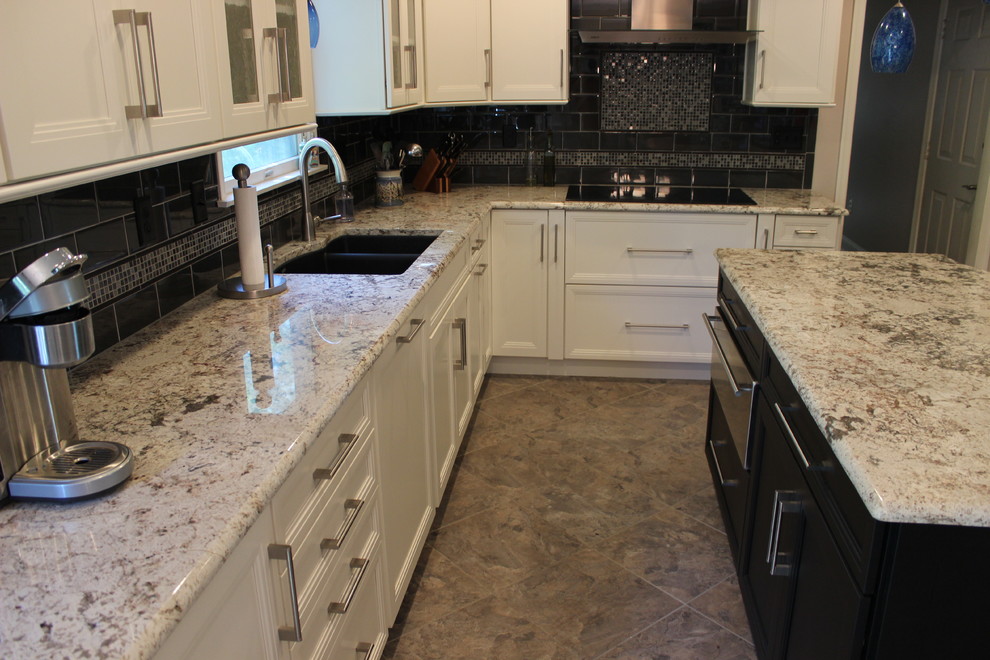 Foto på ett mellanstort funkis kök, med en dubbel diskho, luckor med infälld panel, vita skåp, granitbänkskiva, grått stänkskydd, stänkskydd i glaskakel, rostfria vitvaror, klinkergolv i porslin och en köksö