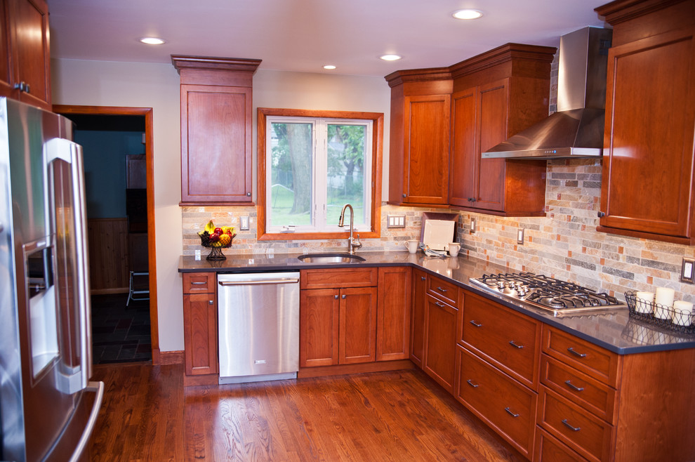 Mid-sized elegant l-shaped medium tone wood floor eat-in kitchen photo in New York with an undermount sink, flat-panel cabinets, medium tone wood cabinets, granite countertops, multicolored backsplash, stone tile backsplash, stainless steel appliances and no island