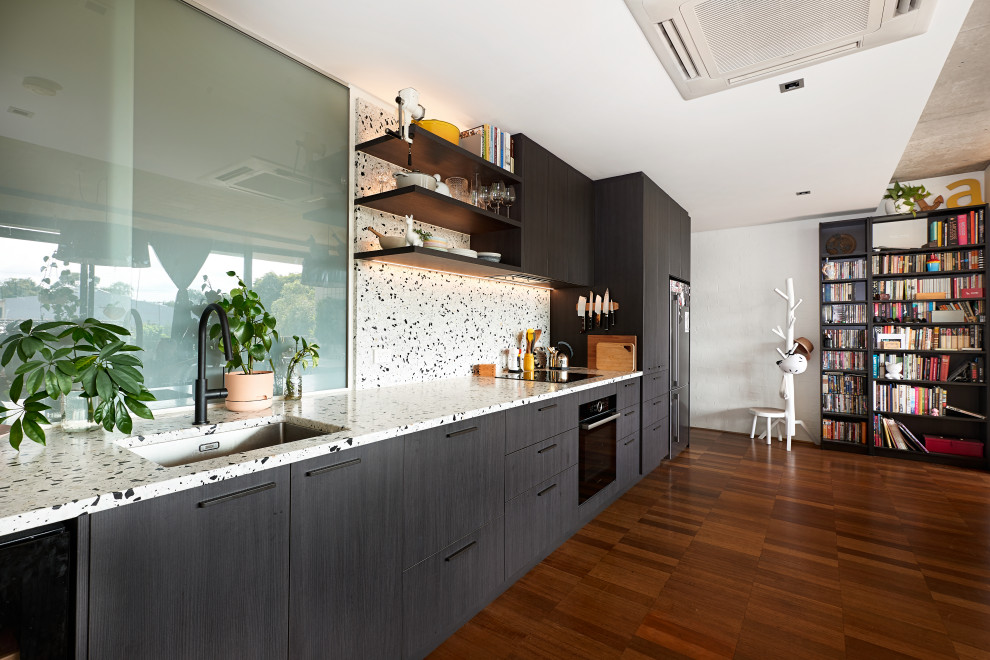 Idéer för funkis linjära vitt kök med öppen planlösning, med en undermonterad diskho, släta luckor, bruna skåp, bänkskiva i kvarts, vitt stänkskydd, stänkskydd i stenkakel, svarta vitvaror, bambugolv och brunt golv