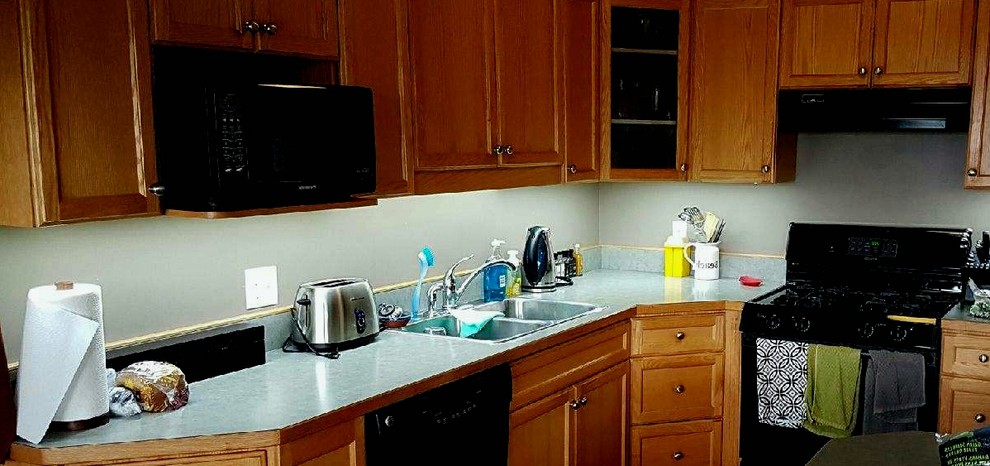 Mittelgroße Moderne Wohnküche in L-Form mit Einbauwaschbecken, flächenbündigen Schrankfronten, hellbraunen Holzschränken, Granit-Arbeitsplatte, Küchenrückwand in Grau, Rückwand aus Keramikfliesen, schwarzen Elektrogeräten, hellem Holzboden und Kücheninsel in Edmonton