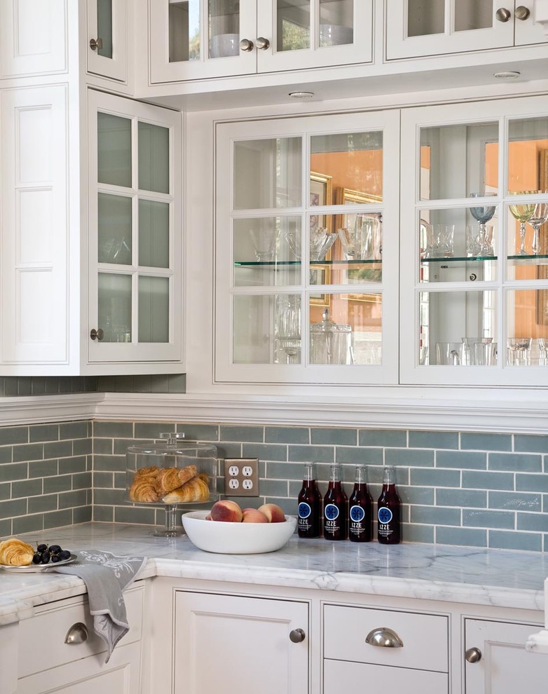 Modelo de cocina tradicional con armarios tipo vitrina, salpicadero de azulejos tipo metro, fregadero sobremueble y electrodomésticos de acero inoxidable