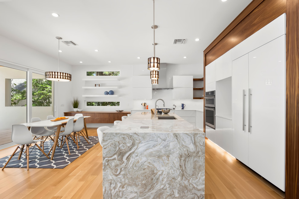 Inspiration for a large modern l-shaped light wood floor and beige floor open concept kitchen remodel in Tampa with a double-bowl sink, flat-panel cabinets, quartzite countertops, white backsplash, ceramic backsplash, stainless steel appliances, an island and multicolored countertops
