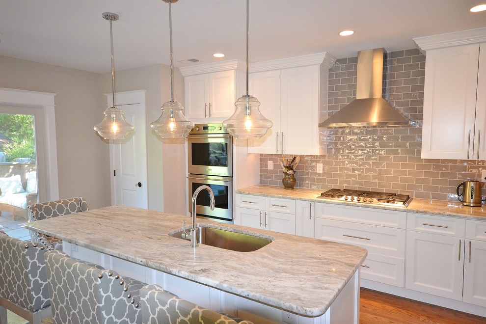 Eat-in kitchen - large traditional single-wall medium tone wood floor eat-in kitchen idea in Philadelphia with an undermount sink, raised-panel cabinets, white cabinets, granite countertops, brown backsplash, subway tile backsplash, stainless steel appliances and an island