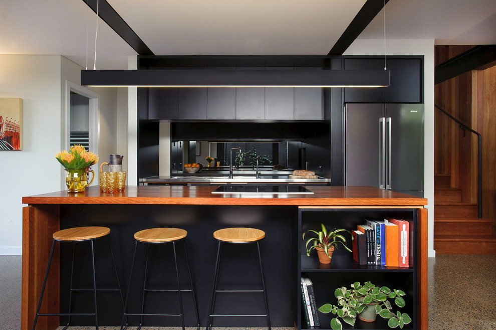 Idéer för ett mellanstort modernt kök, med en integrerad diskho, släta luckor, svarta skåp, träbänkskiva, rostfria vitvaror, betonggolv, flera köksöar, spegel som stänkskydd och grått golv