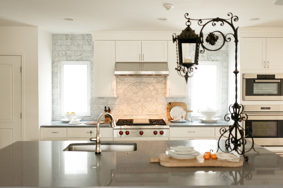 Exempel på ett mellanstort klassiskt grå grått kök, med en undermonterad diskho, luckor med infälld panel, vita skåp, bänkskiva i kvarts, vitt stänkskydd, stänkskydd i porslinskakel, rostfria vitvaror, ljust trägolv, en köksö och beiget golv