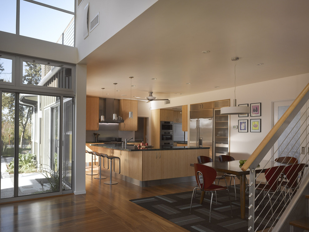 Immagine di una cucina abitabile design con ante lisce, ante in legno chiaro e elettrodomestici in acciaio inossidabile