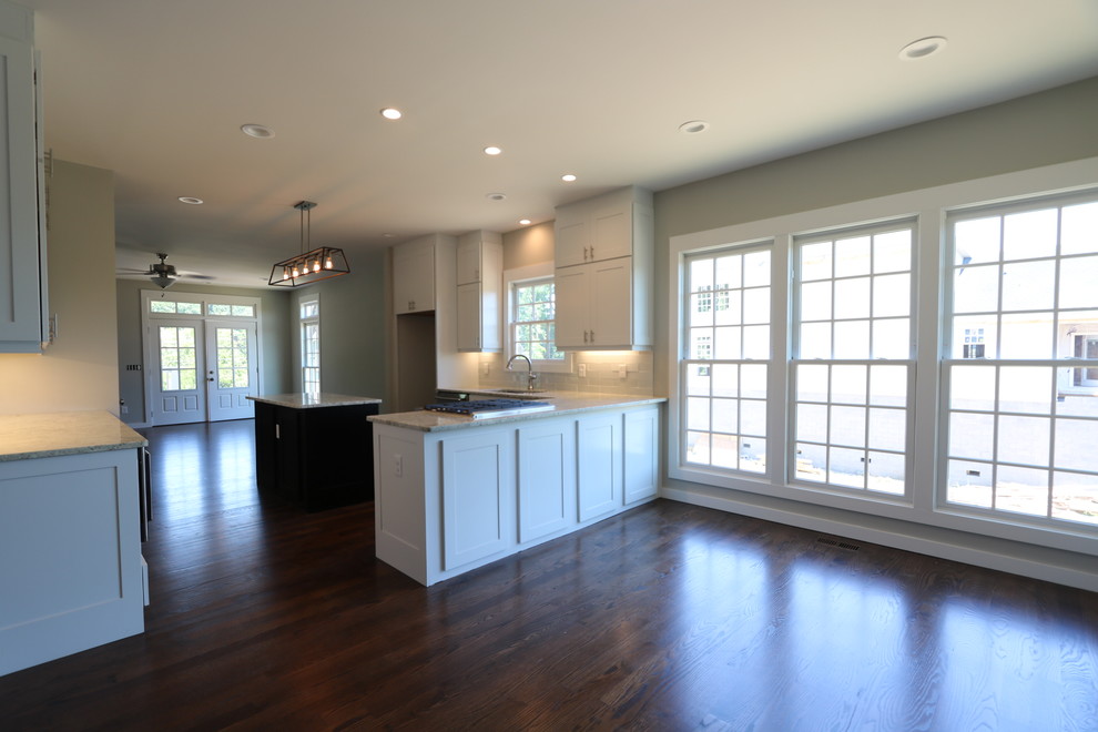Example of a classic medium tone wood floor eat-in kitchen design in Nashville with white cabinets, granite countertops, stainless steel appliances and an island