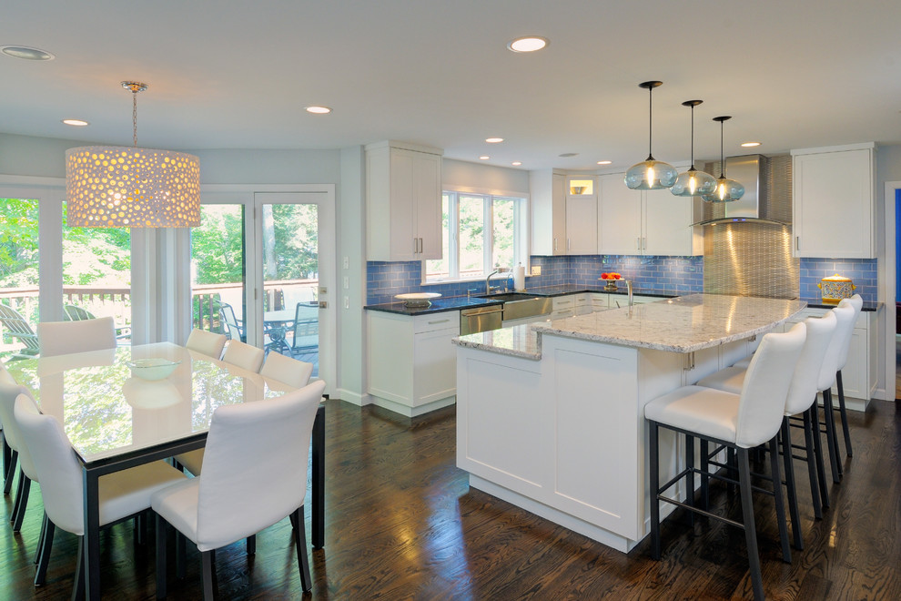 Example of a huge trendy l-shaped dark wood floor and brown floor eat-in kitchen design in Bridgeport with a farmhouse sink, shaker cabinets, white cabinets, granite countertops, blue backsplash, subway tile backsplash, stainless steel appliances and an island
