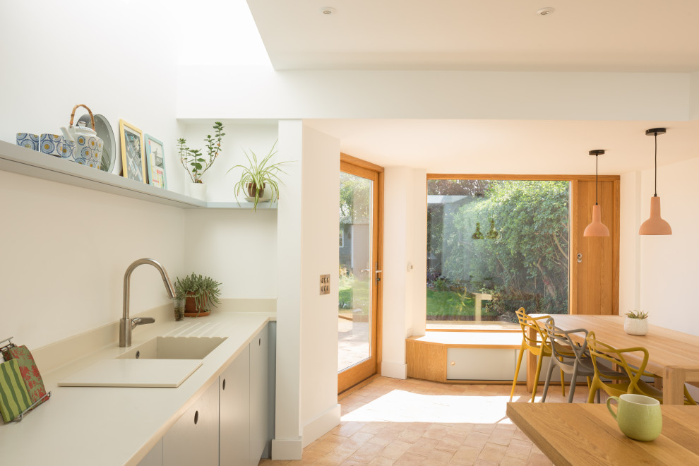 Exempel på ett mellanstort modernt beige beige kök, med en integrerad diskho, släta luckor, blå skåp, bänkskiva i koppar, vitt stänkskydd, rostfria vitvaror, klinkergolv i terrakotta, en köksö och rosa golv