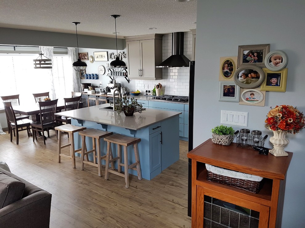 Mittelgroße Klassische Wohnküche mit Doppelwaschbecken, Schrankfronten im Shaker-Stil, blauen Schränken, Quarzit-Arbeitsplatte, Küchenrückwand in Weiß, schwarzen Elektrogeräten, Vinylboden, Kücheninsel und grauer Arbeitsplatte in Edmonton