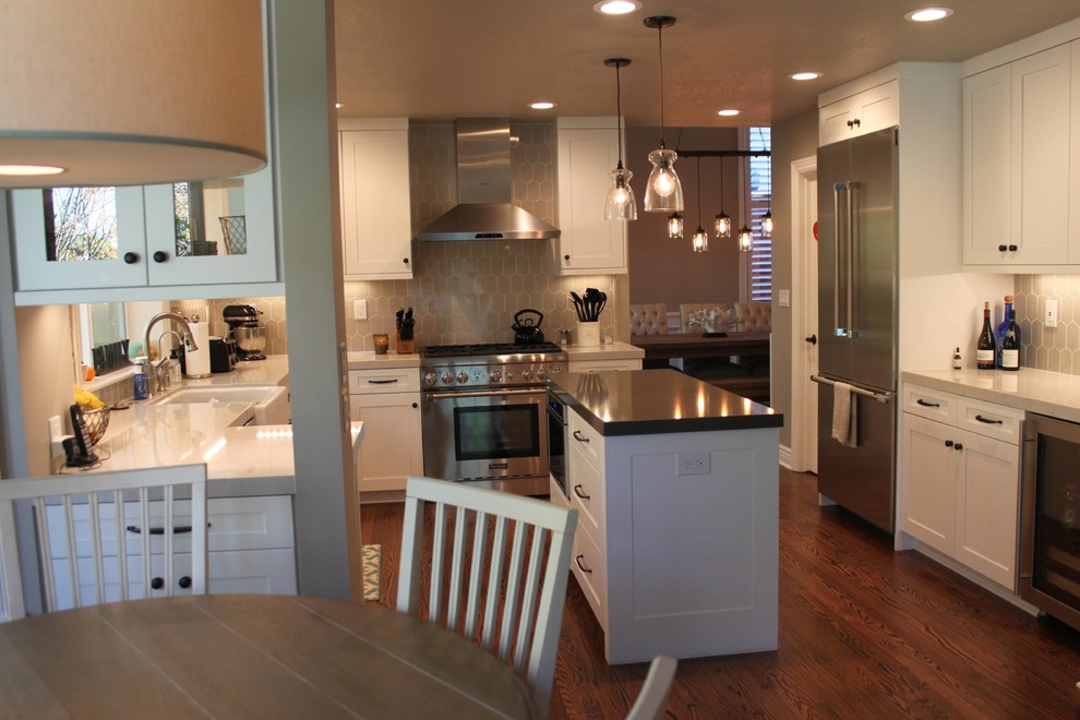 Design ideas for a large traditional u-shaped kitchen/diner in Sacramento with shaker cabinets, white cabinets, grey splashback, stainless steel appliances, dark hardwood flooring, an island, a belfast sink, engineered stone countertops and porcelain splashback.