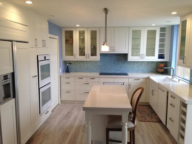 Foto på ett avskilt, litet funkis u-kök, med en rustik diskho, luckor med infälld panel, vita skåp, bänkskiva i kvarts, blått stänkskydd, stänkskydd i keramik, vita vitvaror, ljust trägolv och en köksö