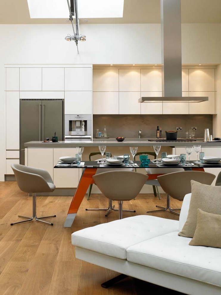 Inspiration for a modern galley open concept kitchen remodel in London with flat-panel cabinets, white cabinets, gray backsplash and stainless steel appliances