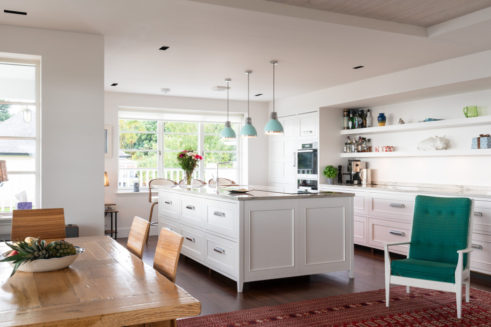 This is an example of a classic galley kitchen/diner in Other with recessed-panel cabinets, white cabinets, stainless steel appliances, dark hardwood flooring, an island, brown floors and grey worktops.