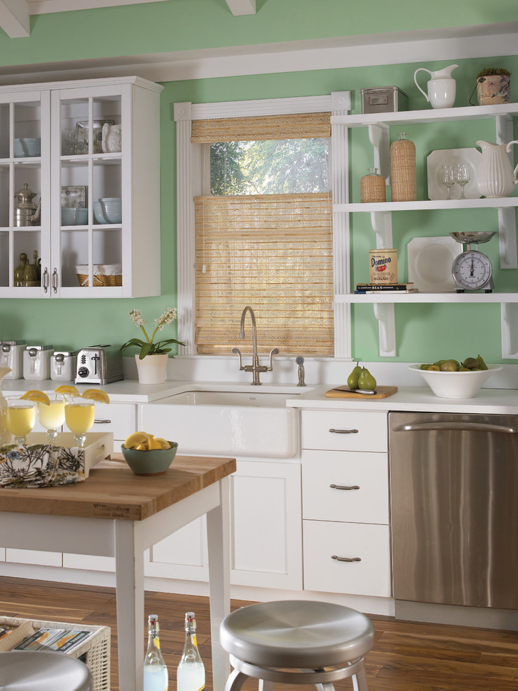 Bild på ett amerikanskt kök, med en rustik diskho, luckor med glaspanel, vita skåp, rostfria vitvaror, mellanmörkt trägolv, en köksö och brunt golv