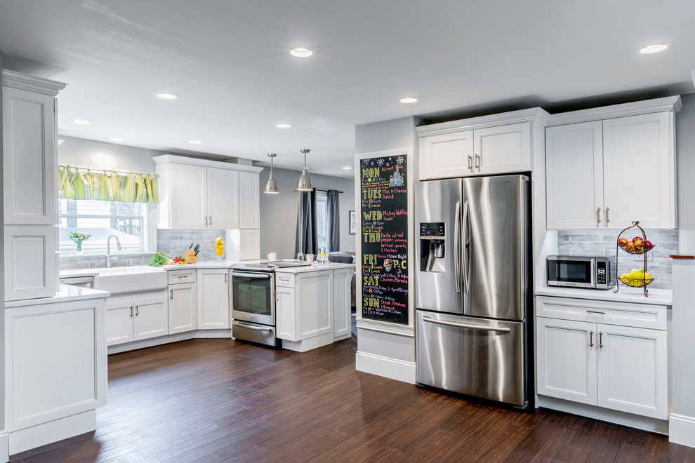 Large classic u-shaped kitchen/diner in Boston with a belfast sink, white cabinets, grey splashback, stainless steel appliances, bamboo flooring and a breakfast bar.