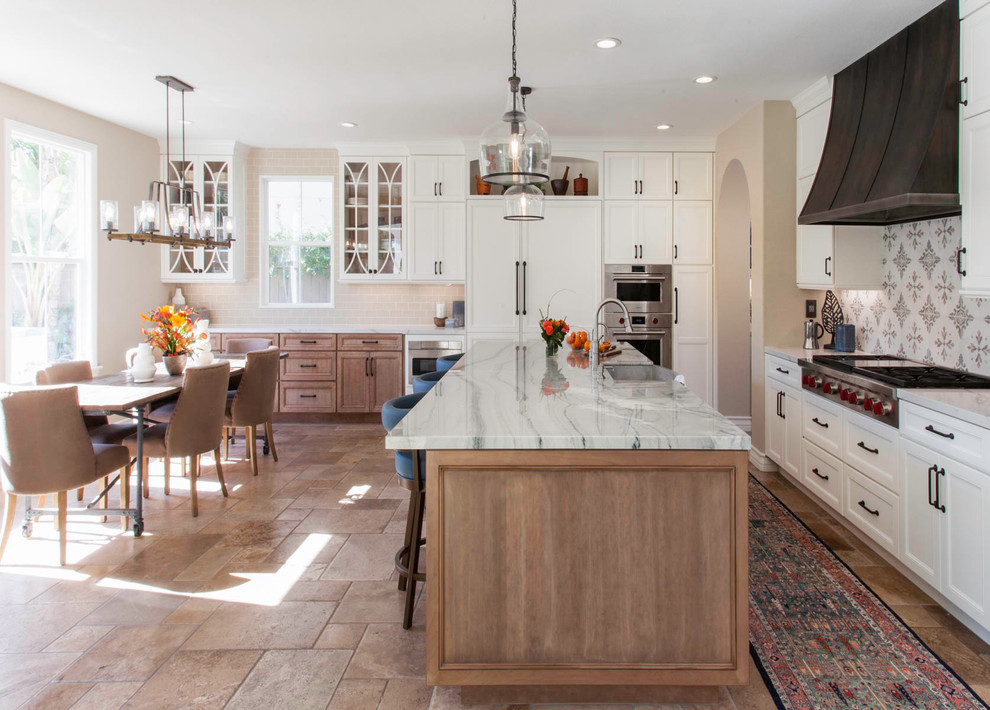 Example of a large transitional l-shaped medium tone wood floor and beige floor open concept kitchen design in San Diego with a farmhouse sink, recessed-panel cabinets, white cabinets, quartz countertops, white backsplash, marble backsplash, stainless steel appliances, an island and white countertops