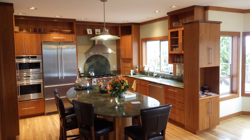 This is an example of a large contemporary u-shaped kitchen/diner in Seattle with a submerged sink, medium wood cabinets, stainless steel appliances, light hardwood flooring and an island.