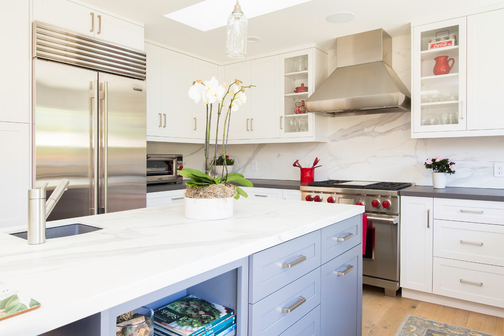 Example of a mid-sized transitional u-shaped light wood floor kitchen design in San Francisco with shaker cabinets, white cabinets, white backsplash and an island