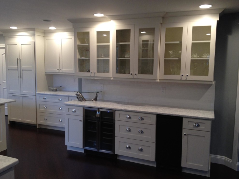 Large classic galley kitchen/diner in New York with a belfast sink, shaker cabinets, white cabinets, marble worktops, white splashback, cement tile splashback, integrated appliances, dark hardwood flooring and multiple islands.