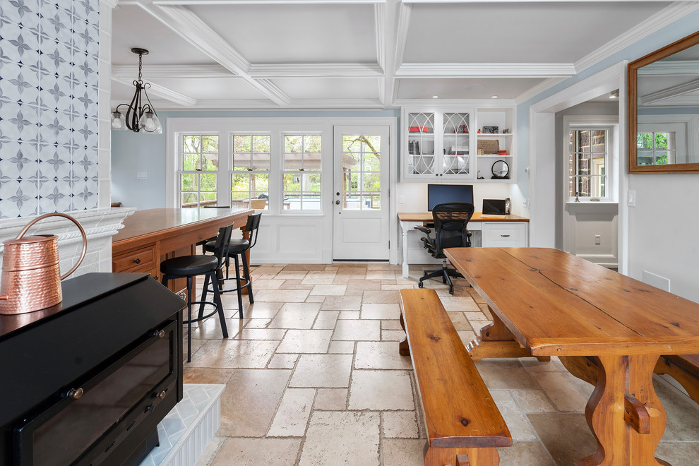 Inredning av ett klassiskt avskilt, stort blå blått kök, med en rustik diskho, luckor med upphöjd panel, skåp i mellenmörkt trä, granitbänkskiva, flerfärgad stänkskydd, stänkskydd i porslinskakel, svarta vitvaror, kalkstensgolv, en halv köksö och flerfärgat golv
