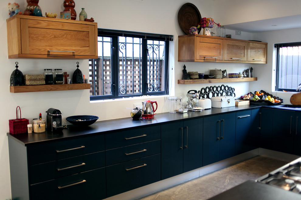 Cette photo montre une cuisine chic en L avec un placard à porte plane et des portes de placard bleues.