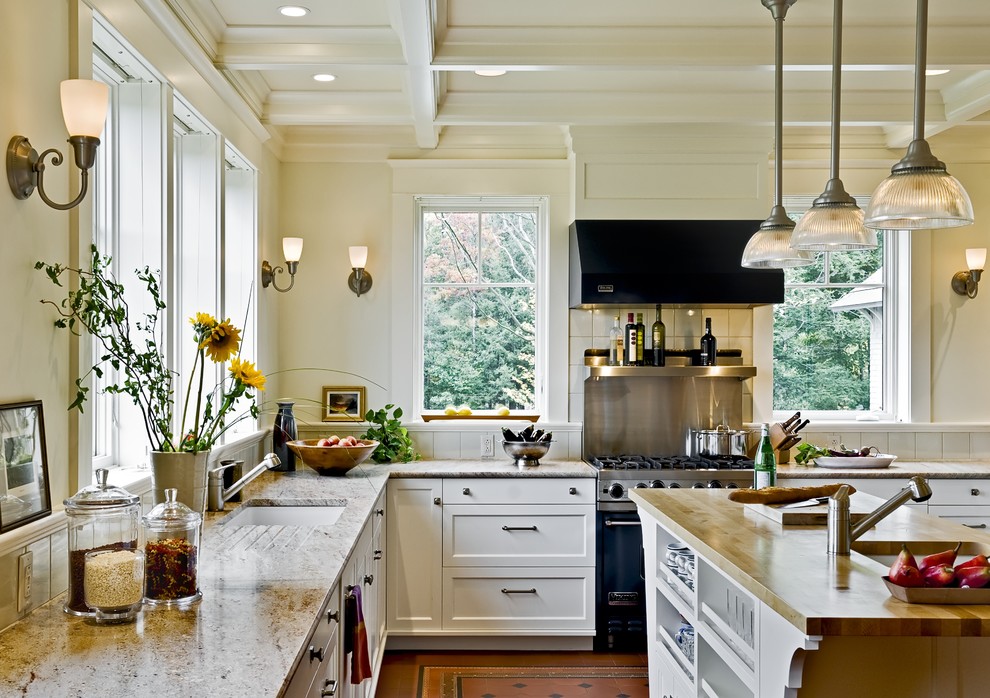 Example of a classic kitchen design in Burlington with wood countertops, an undermount sink, recessed-panel cabinets, white cabinets and black appliances