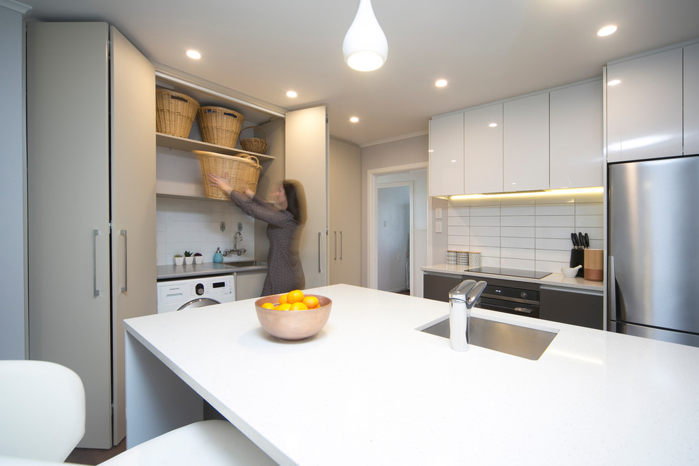 Einzeilige, Kleine Moderne Küche mit Waschbecken, flächenbündigen Schrankfronten und Laminat-Arbeitsplatte in Auckland