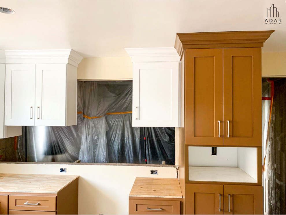 Modelo de cocina clásica renovada grande con armarios con paneles empotrados, encimera de granito, salpicadero con mosaicos de azulejos, electrodomésticos de acero inoxidable y encimeras blancas