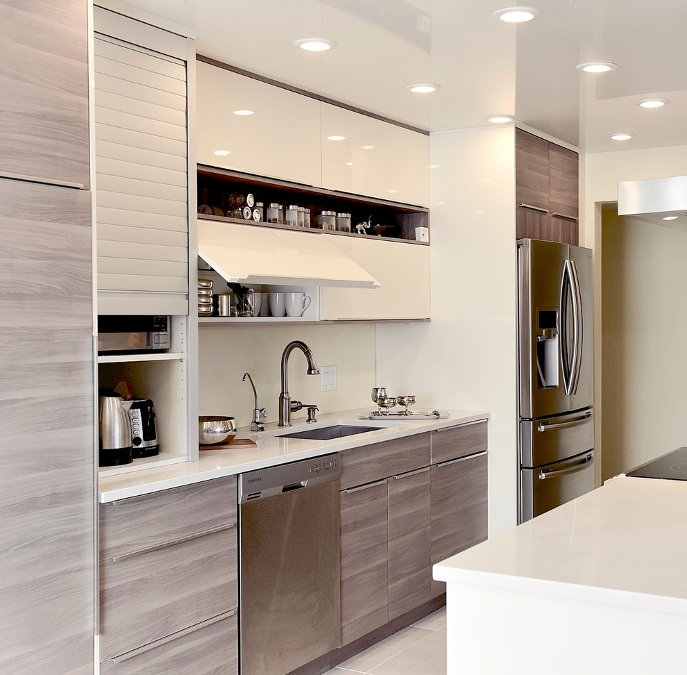 Immagine di una cucina minimalista di medie dimensioni con lavello sottopiano, ante lisce, ante in legno chiaro, top in quarzo composito e elettrodomestici in acciaio inossidabile