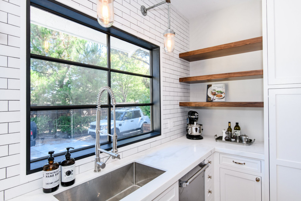 Photo of a medium sized rural u-shaped enclosed kitchen in San Francisco with a submerged sink, shaker cabinets, white cabinets, engineered stone countertops, white splashback, metro tiled splashback, stainless steel appliances, light hardwood flooring, an island, brown floors and white worktops.