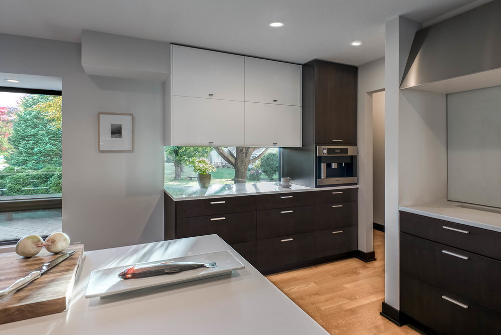 Photo of a large contemporary kitchen/diner in Other with a double-bowl sink, flat-panel cabinets, dark wood cabinets, engineered stone countertops, white splashback, stone slab splashback, stainless steel appliances, light hardwood flooring, an island, brown floors and white worktops.