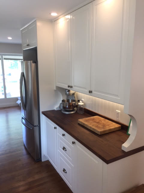 This is an example of a medium sized rural l-shaped open plan kitchen in Calgary with a double-bowl sink, raised-panel cabinets, white cabinets, wood worktops, white splashback, wood splashback, stainless steel appliances, dark hardwood flooring and an island.
