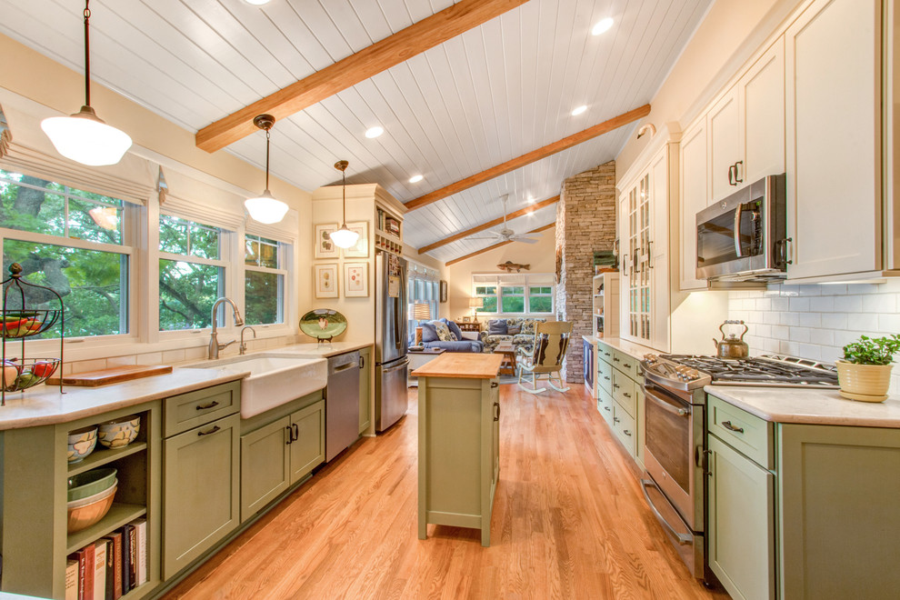 Inspiration for a mid-sized farmhouse galley light wood floor and beige floor eat-in kitchen remodel in Milwaukee with a farmhouse sink, green cabinets, beige backsplash, subway tile backsplash, stainless steel appliances, an island, shaker cabinets and quartz countertops