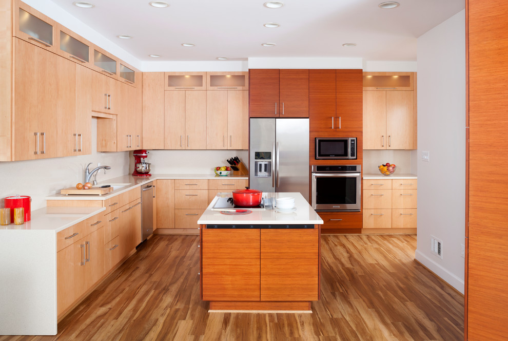 Idée de décoration pour une grande cuisine américaine design en L avec un sol en bois brun et îlot.