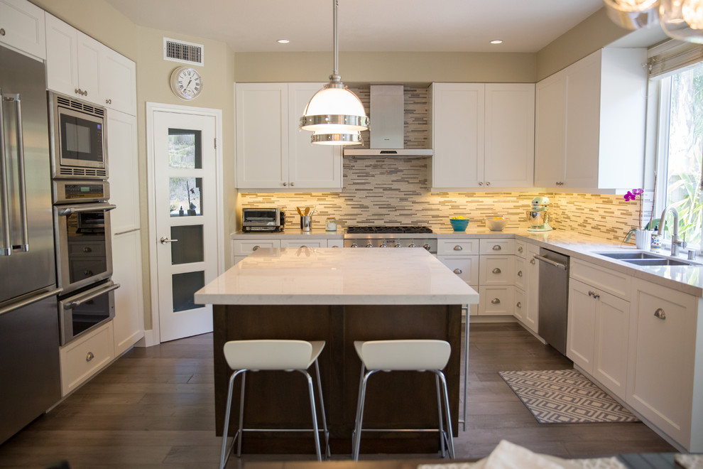 Large trendy u-shaped light wood floor eat-in kitchen photo in San Diego with a double-bowl sink, beaded inset cabinets, light wood cabinets, limestone countertops, multicolored backsplash, glass tile backsplash, stainless steel appliances and an island