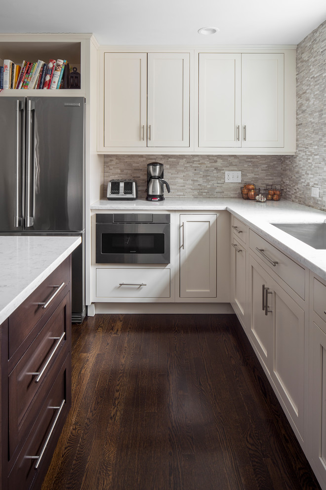 Example of a large transitional l-shaped dark wood floor enclosed kitchen design in Boston with an undermount sink, shaker cabinets, white cabinets, marble countertops, gray backsplash, stone tile backsplash, stainless steel appliances and an island