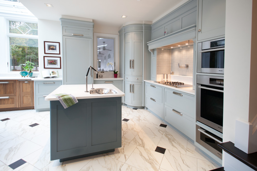 Photo of a medium sized contemporary l-shaped kitchen/diner in DC Metro with recessed-panel cabinets, blue cabinets, a submerged sink, grey splashback, glass tiled splashback, stainless steel appliances, marble flooring, an island, white floors, engineered stone countertops and turquoise worktops.